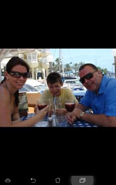 three people sitting at a table with wine glasses