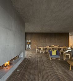 an empty room with tables and chairs around a fire place in the middle of it