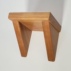 a small wooden stool sitting on top of a white wall