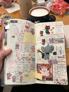 an open book with stickers on it and a cup of coffee in the background