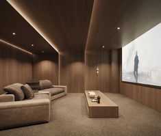 an empty room with couches and a large screen in the corner on the wall