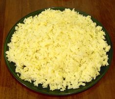 a green plate topped with rice on top of a wooden table