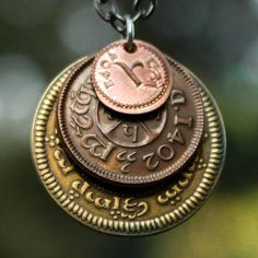 a close up of a coin on a chain hanging from a necklace with an inscription