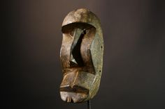 a carved wooden mask on a stand against a dark background