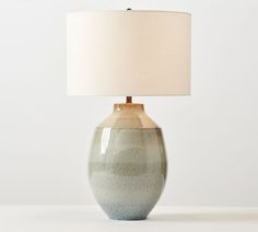 a lamp that is on top of a table next to a white wall and floor