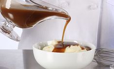 someone pouring caramel sauce into a bowl of mashed potatoes in a white bowl