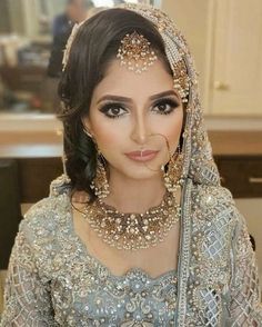 a woman wearing a bridal outfit with jewelry on her head and in the background