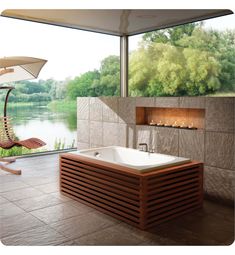 a large bath tub sitting next to a window with a view of the water and trees