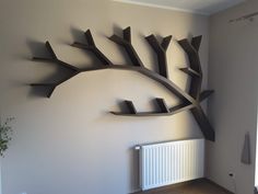 a large metal tree sculpture mounted to the side of a white wall next to a radiator