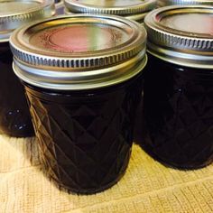 four jars filled with jam sitting on top of a table