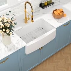 a kitchen with blue cabinets and marble counter tops, gold faucets and flowers