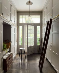 a ladder is leaning against the wall in front of a white entryway with large windows