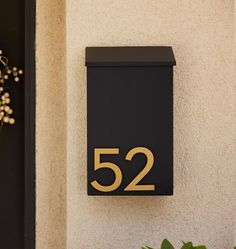 a black mailbox with the number 522 on it next to a house plant