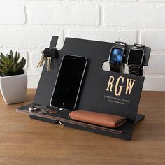 an iphone and other electronics are sitting in a holder on a table next to a cactus