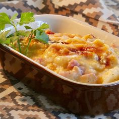 a casserole dish with meat and vegetables in it on a patterned tablecloth