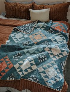 a bed with a blue and orange quilt on it