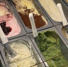 an assortment of ice creams in trays with spoons