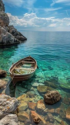 a small boat sitting on top of a body of water next to rocks and boulders