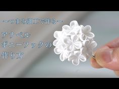 a hand holding a small white flower in it's left hand with japanese writing on the background