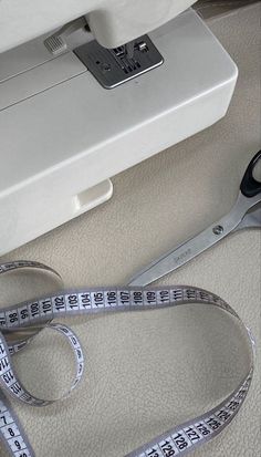 a pair of scissors and measuring tape sit next to a sewing machine