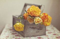 yellow roses in a wooden box on a table