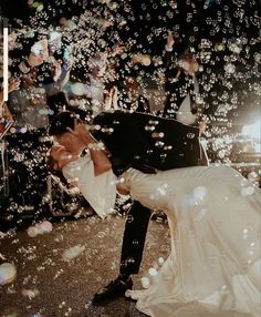 a bride and groom kissing in front of bubbles on the ground at their wedding reception