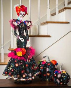 a woman dressed in black and red is standing next to pumpkins on the stairs