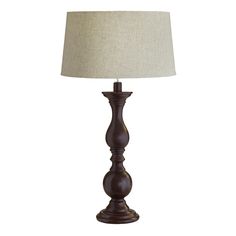 a lamp that is sitting on top of a white table cloth with a beige shade