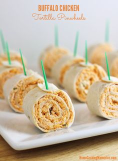 rolled up tortilla sandwiches on a plate with toothpicks in the middle