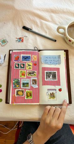 a person sitting at a table with an open book and various stamps on it, next to a cup of coffee