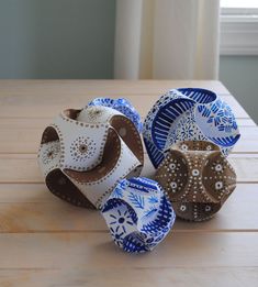 four decorative bowls sitting on top of a wooden table in front of a white window