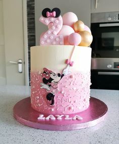 a pink and white cake with minnie mouse decorations