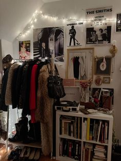 a room filled with lots of clothes and pictures on the wall next to a book shelf