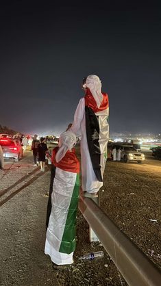 a person standing on the side of a road holding an american and irish flag scarf