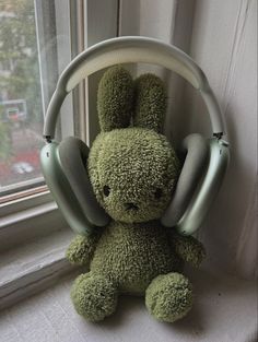 a green stuffed animal with headphones in front of a window