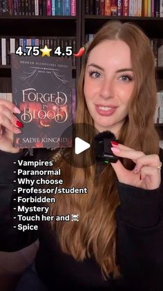 a woman holding up a book in front of a bookshelf