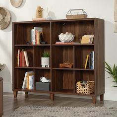 a book shelf with many books on top of it in a living room next to a rug