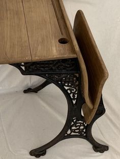 an old wooden table with metal legs on a white cloth covered background, showing the edge of the table