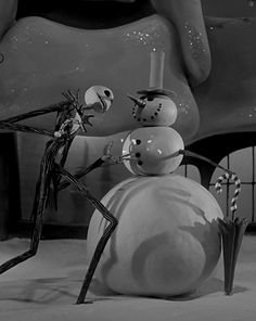 a black and white photo of a snowman in front of a giant fake man