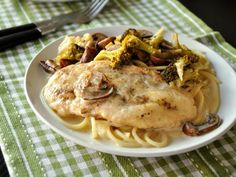 a white plate topped with chicken and pasta covered in mushrooms, broccoli and mushroom gravy