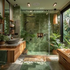 a green tiled bathroom with two sinks and large mirrors on the wall, along with potted plants