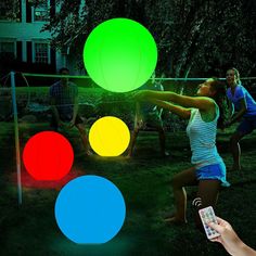 several people are playing with glowing balls in the yard at night, and one person is holding a cell phone