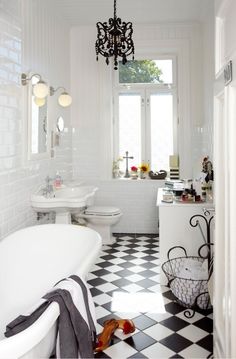 a black and white checkered floor in a bathroom with a chandelier hanging from the ceiling