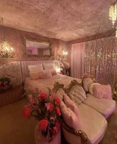 a bedroom decorated in pink and gold with chandeliers on the ceiling, couches, and bed