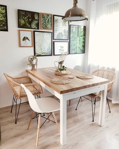 a dining room table with chairs and pictures on the wall behind it in front of a window