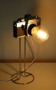 an old fashioned camera on a metal stand with a light bulb attached to it's side