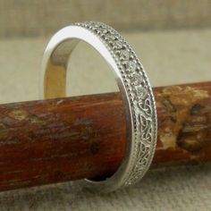 a silver ring sitting on top of a piece of wood next to a wooden stick