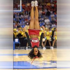 a cheerleader is doing a handstand on the court with her feet in the air