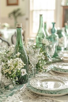 the table is set with green glassware and white flowers in vases on it