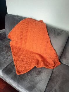 an orange blanket sitting on top of a gray couch